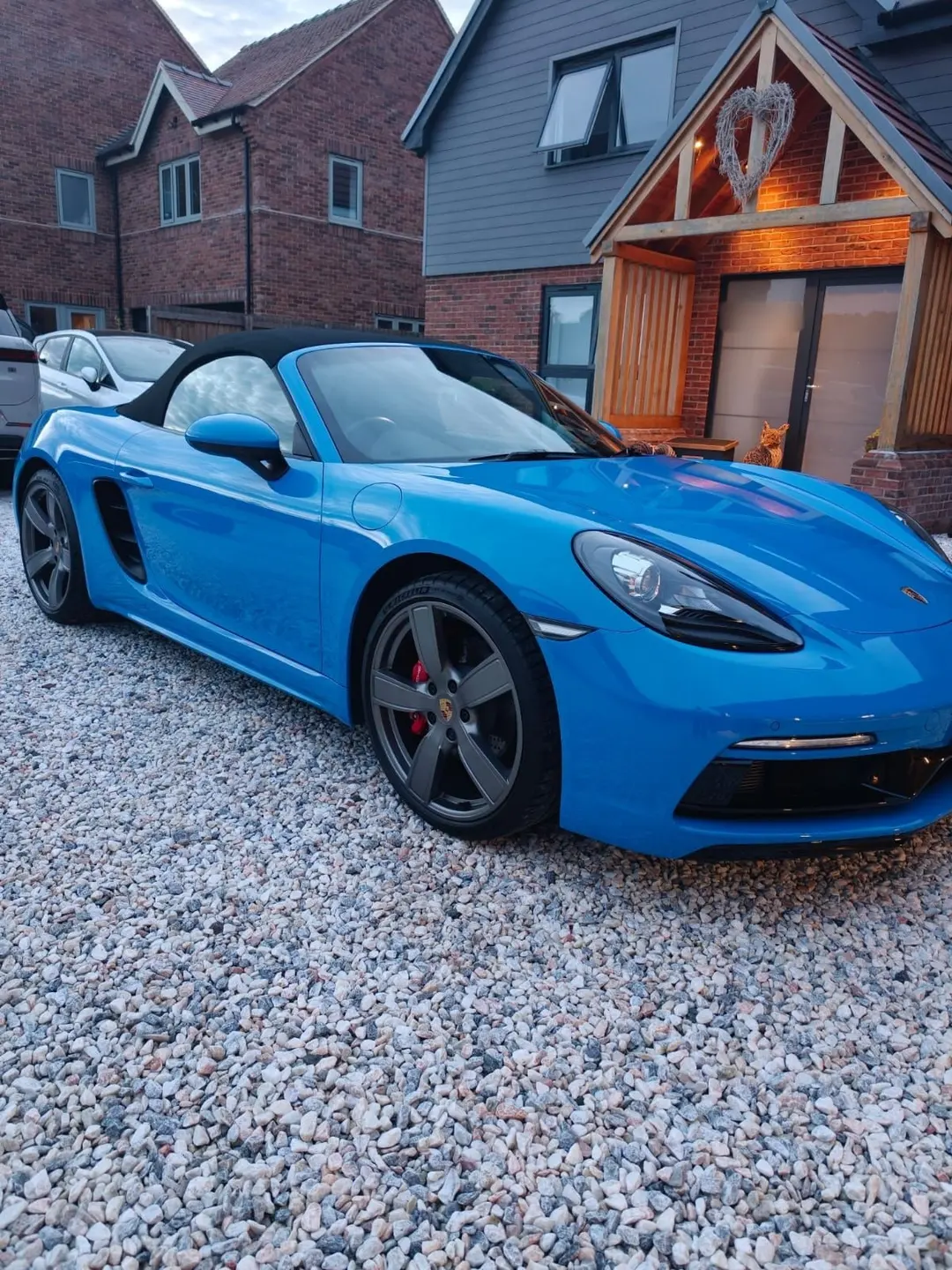 Blue Porsche 718 Boxster on a gravel driveway